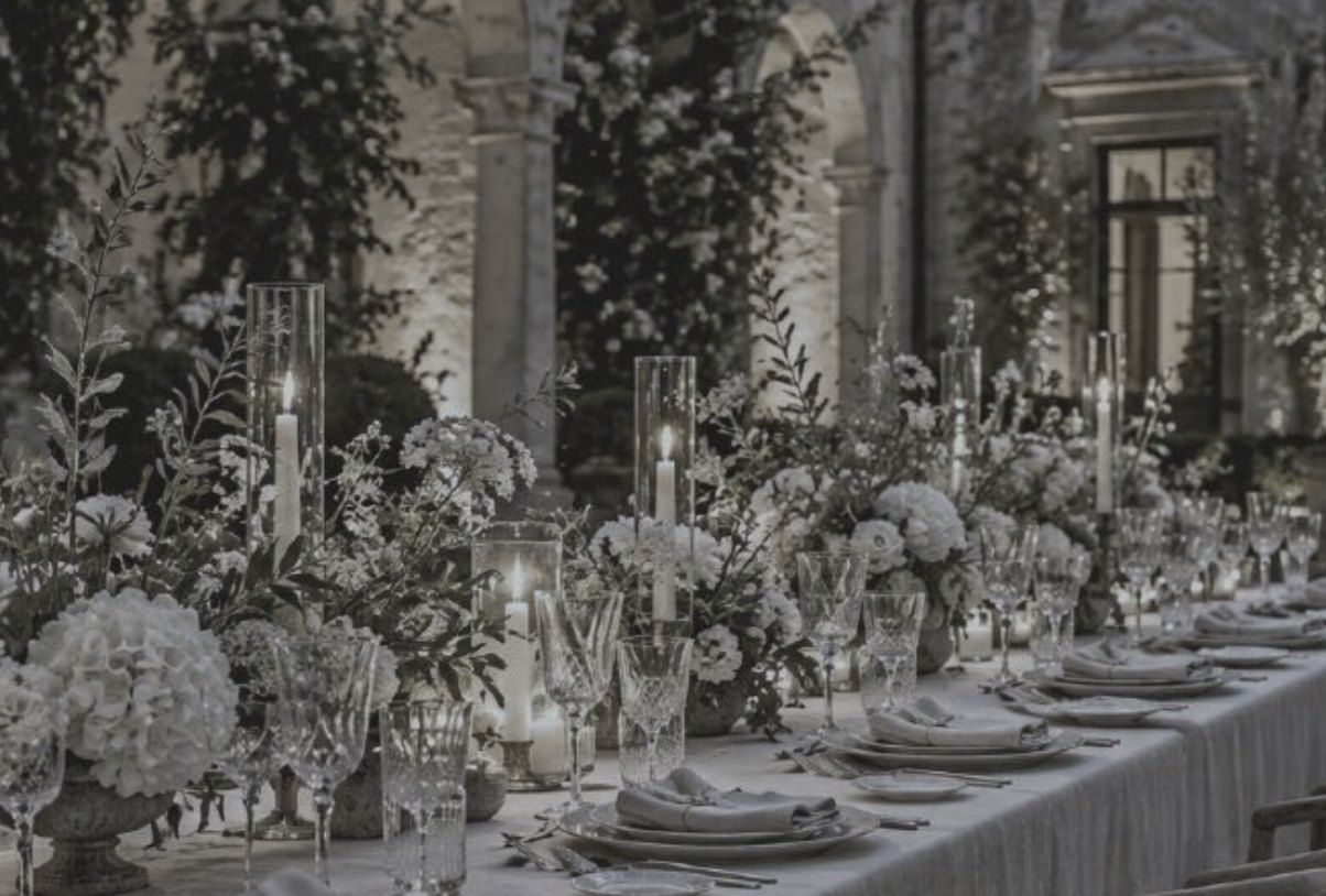 Candlelit dinner table with flowers in a courtyard